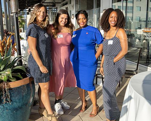 Four female alumni standing outside on porch at Santa Monica event..