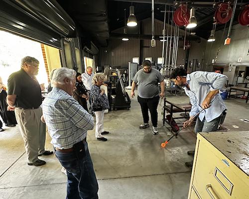 Members of Port City Craftsman watching glass blowing in the studio at USA.